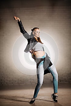 Young female in leather jacket dancing in free style