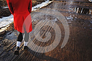 Young female legs walking towards the sunset on a dirt road in the spring