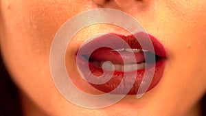 Young female licking her lips. Close up shot of beautiful woman tongue licking her lips with bright deep red plum berry