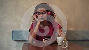 Young female listening to music and using device while sitting at table in cafe spbas.