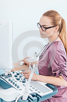 Young female londe doctor with black glasses. Ultrasound scanner in the hands of a doctor. Diagnostics. Sonography.