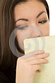 Young female looking down hiding mouth with book