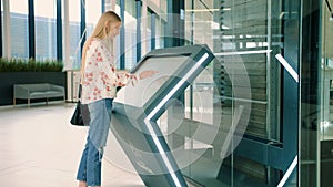 Young female looking for right direction on navigation board in modern mall.