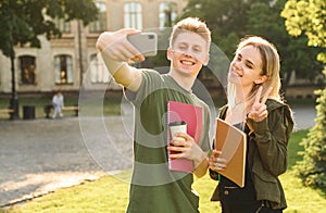 Young female and male friends in the park posing for selfie on smartphone camera, millenial students taking photo on mobile phone