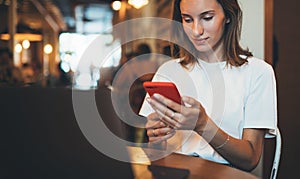 Young female manager holding smartphone using laptop in cafe, hipster girl freelancer writing on mobile phone, businesswoman work