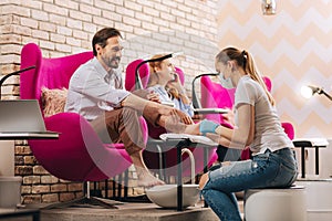 Young female manicurist rubbing male foot