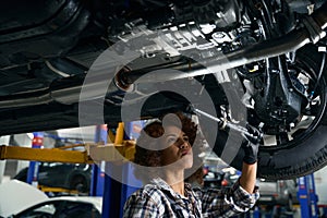 Young female mechanic conducts an inspection of car from below