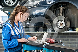 Young Female Mechanic Making Notes In Garage