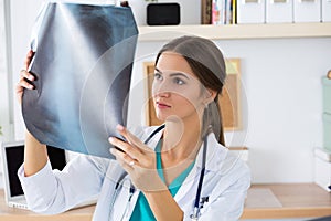 Young female medical doctor or intern looking at lungs x-ray image