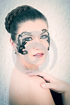 Beautiful Caucasian Model With Decorative Lace and Black Tattoo on Her Face, Touching Her Shoulder, on White Lace Background