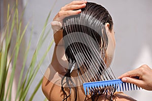 Young Female Model Putting Refreshing Mask On Long Wet Hair With Wooden Comb