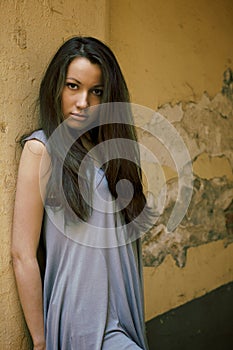 Young female model standing near the old wall