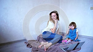 Young female mother and daughter child use gadgets for communica