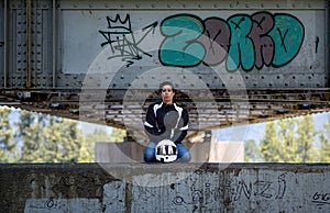 Young female motor cyclist kneeling on a metal bridge structure