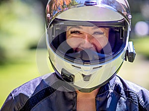 Young female motor cyclist wearing a full fase helmet with visor open smiling