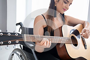 Young female musician in wheelchair playing guitar