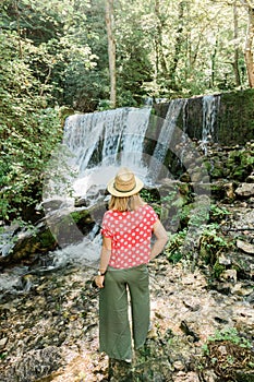 Young female nature explorer standing in front of the waterfall