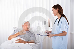 Nurse With Clipboard Visiting Senior Patient