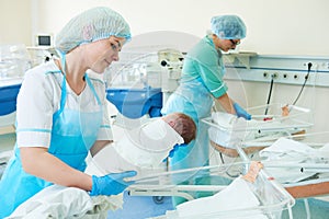 Young female nurse holding a newborn baby in hospital photo