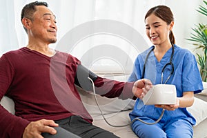 Young female nurse measuring blood pressure for elderly at home. concept health