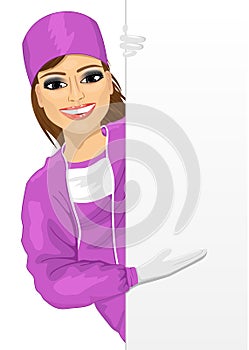Young female nurse in pink scrub suit presenting empty banner