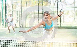Young female paddle tennis player performing left hand forehand