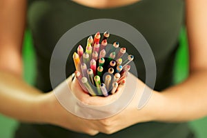 Young female painter holding colored pencils at camera