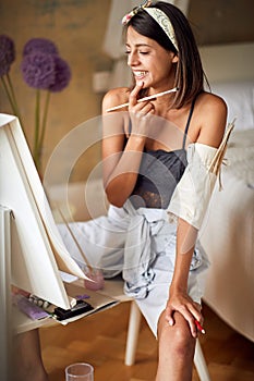 Young female painter watching her painting, satisfied