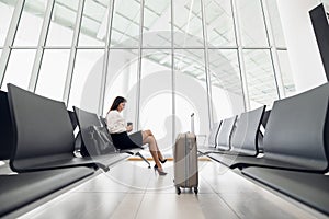 Young female passenger at the airport, using her tablet computer while waiting for her flight