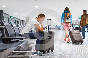 Young female passenger at the airport, using her tablet computer