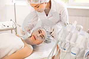 Young female patient receiving high frequency ultrasonic facial procedure