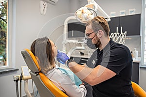 young female patient sits in a dentist& x27;s chair in his office.