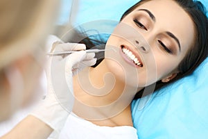 Young female patient visiting dentist office.Beautiful woman with healthy straight white teeth sitting at dental chair