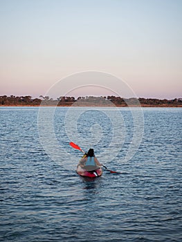 Young female person woman girl in red yellow kayak paddling into sunset clear blue ocean water Mallorca Spain