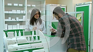 Young female pharmacist hrlping male client to buy tablet at pharmacy