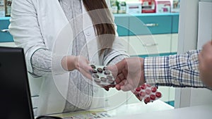 Young female pharmacist offering two variants of medications to the customer. Male purchaser choosing between black and