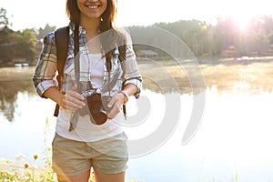 Young female photographer with camera near lake