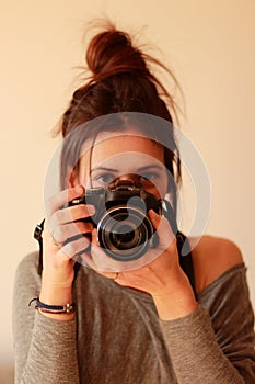 Young female photographer with camera on soft background