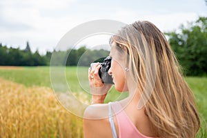 Young female photographer taking a photo of fields in nature