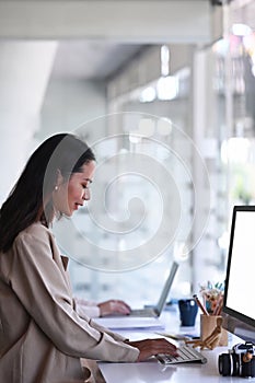 Young female photographer working with computer at modern office.