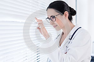 Young female physician smiling while looking through the window