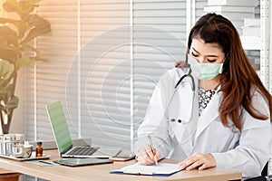 Young female physician wear hygienic mask  writing on cardboard