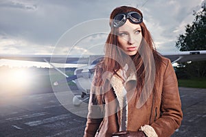 A young female pilot is standing next to a small training plane