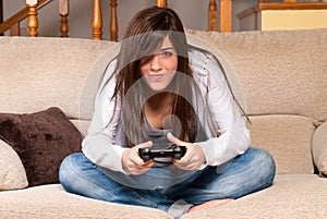 Young female playing video-games concentrating on couch at home