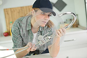 Young female plumber examining mixer tap