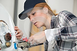 young female plumber working on water heater