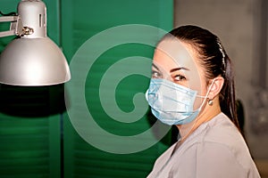 Young female podiatrist with a protective mask looking at the camera in her podiatry clinic.