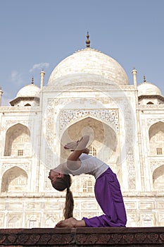 Young female practising Ustrasana or Camel Pose at Taj Mahal