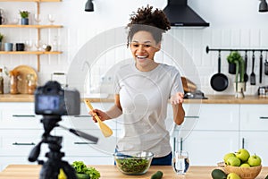 young female preparing salad in home kitchen Beautiful woman using camera to record video of cooking healthy food