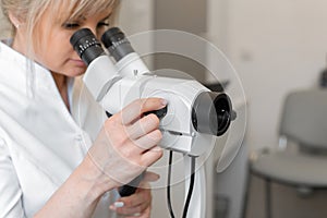 Young female professional gynecologist in the working process, looks into the colposcope photo